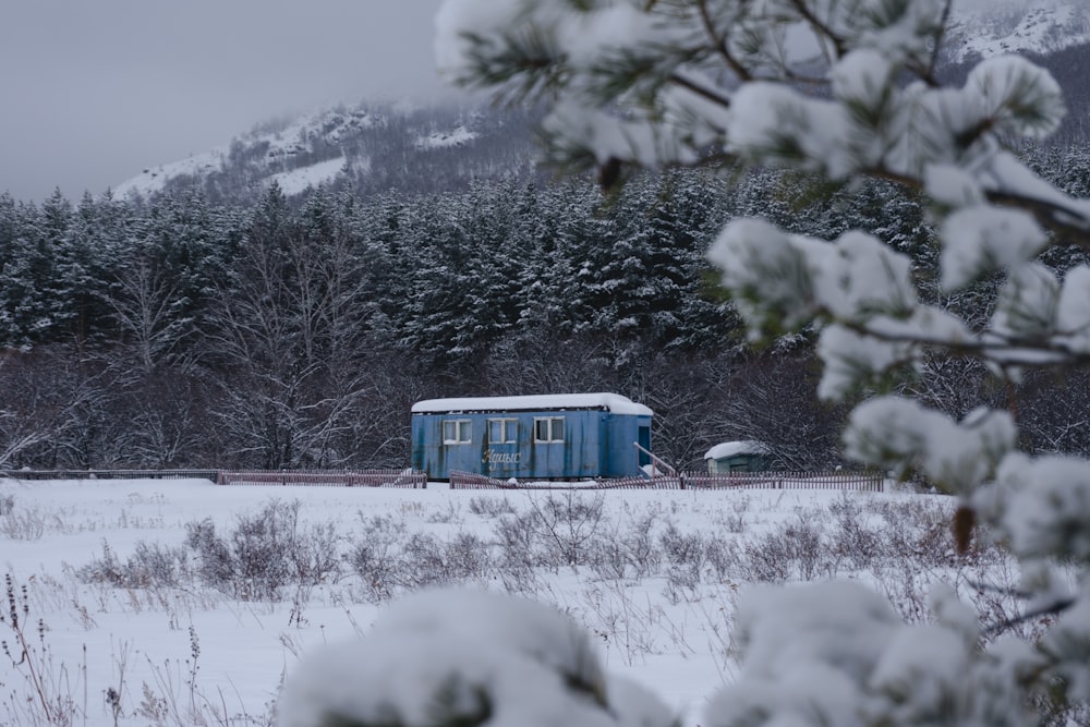 a small blue building sitting in the middle of a snow covered field