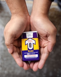 Hands holding a naloxone auto-injector device labeled Evzio, used for opioid emergencies. The device is yellow and purple with instructions for use printed on it.
