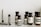 A collection of Aesop branded skincare and grooming products arranged on a light-colored marble surface. The products include small amber glass bottles with black screw caps, a tube, and stick-shaped containers. All labels are black and white, featuring product information in both English and possibly French.