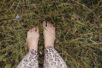 a person standing in the grass with their feet up