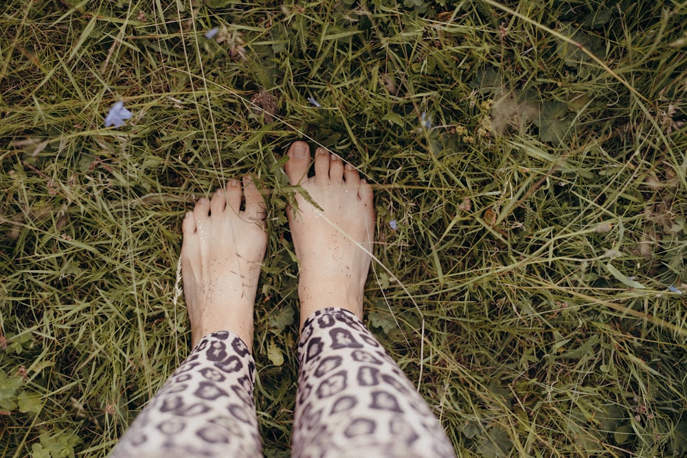 a person standing in the grass with their feet up