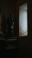 A dimly lit room with religious icons casting long shadows on the walls.