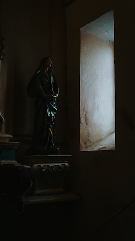 A dimly lit room with religious icons casting long shadows on the walls.