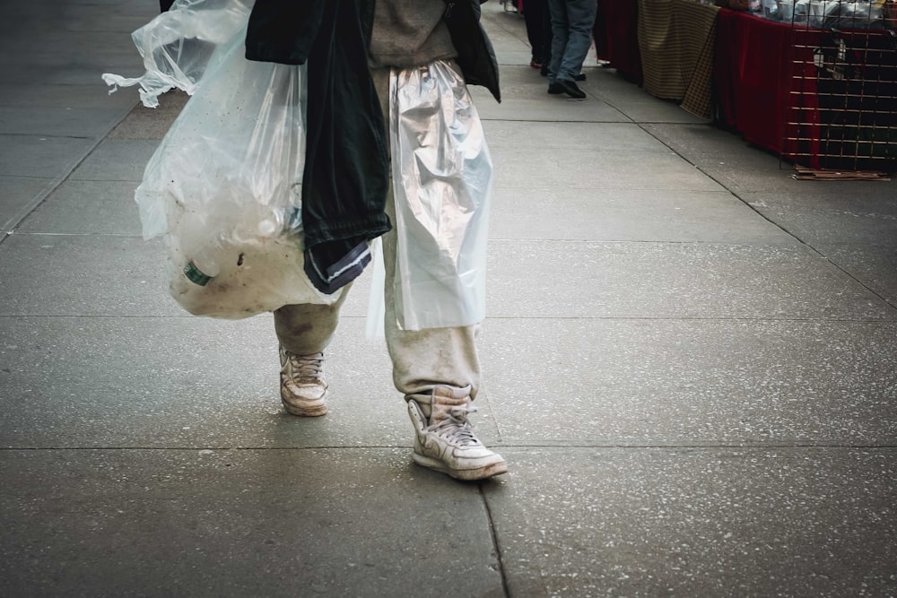 a person walking down a sidewalk carrying bags