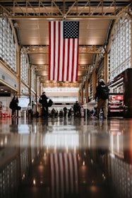 a group of people standing in a building with an american flag hanging from the ceiling