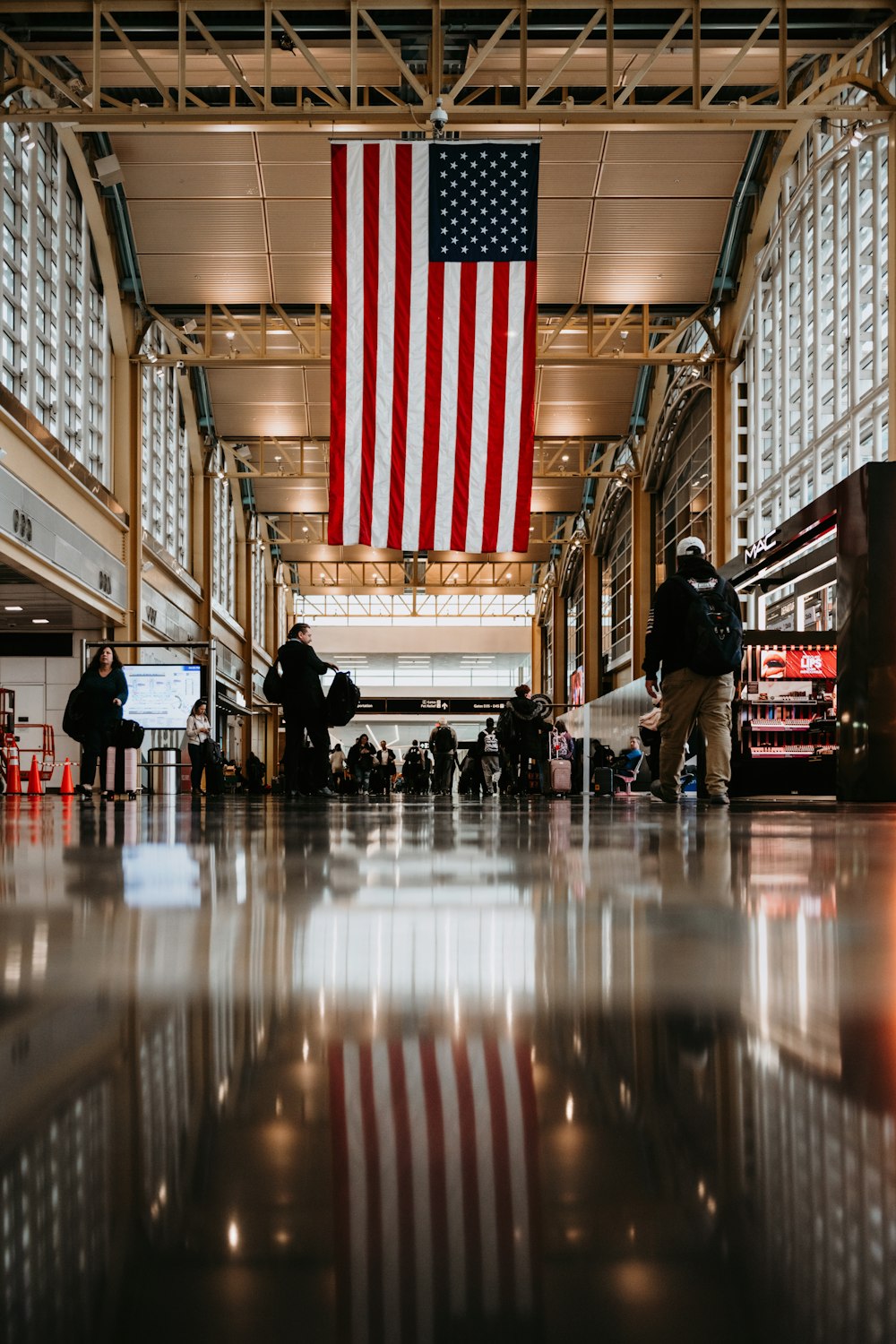 a group of people standing in a building with an american flag hanging from the ceiling