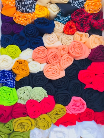 A vibrant display of colorful fabric rolls neatly stacked in a sunlit warehouse.