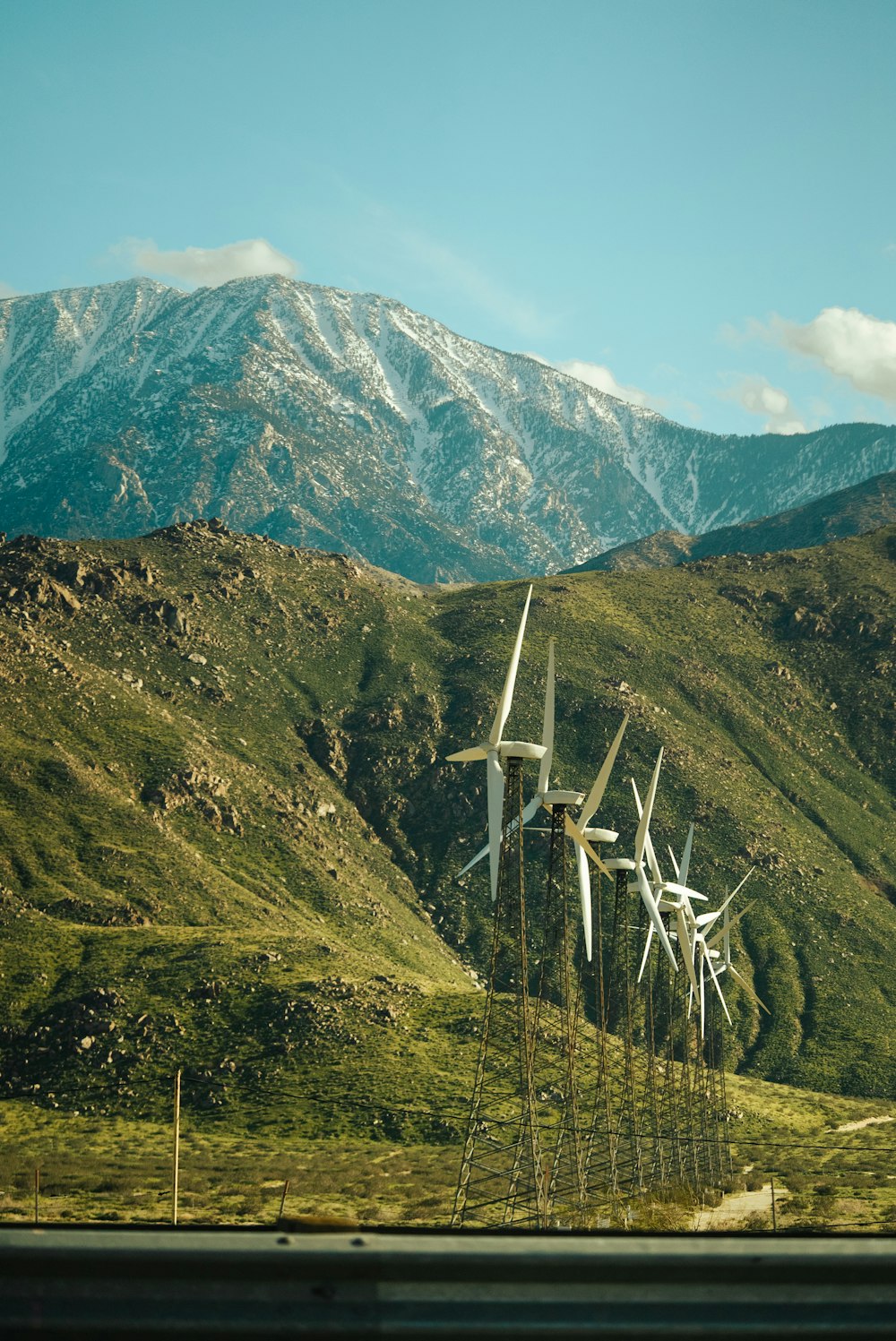 Un montón de molinos de viento en un campo con montañas al fondo