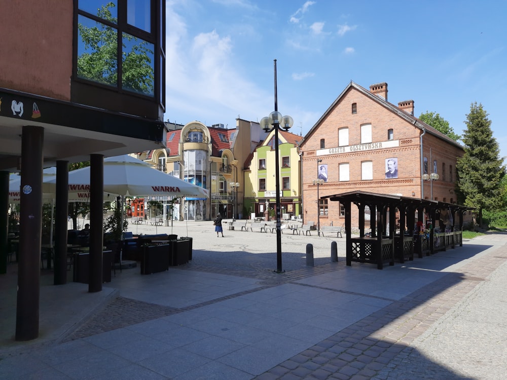 a city square with tables and umbrellas on a sunny day