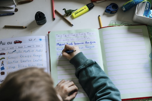 a person writing on a notebook with a pen