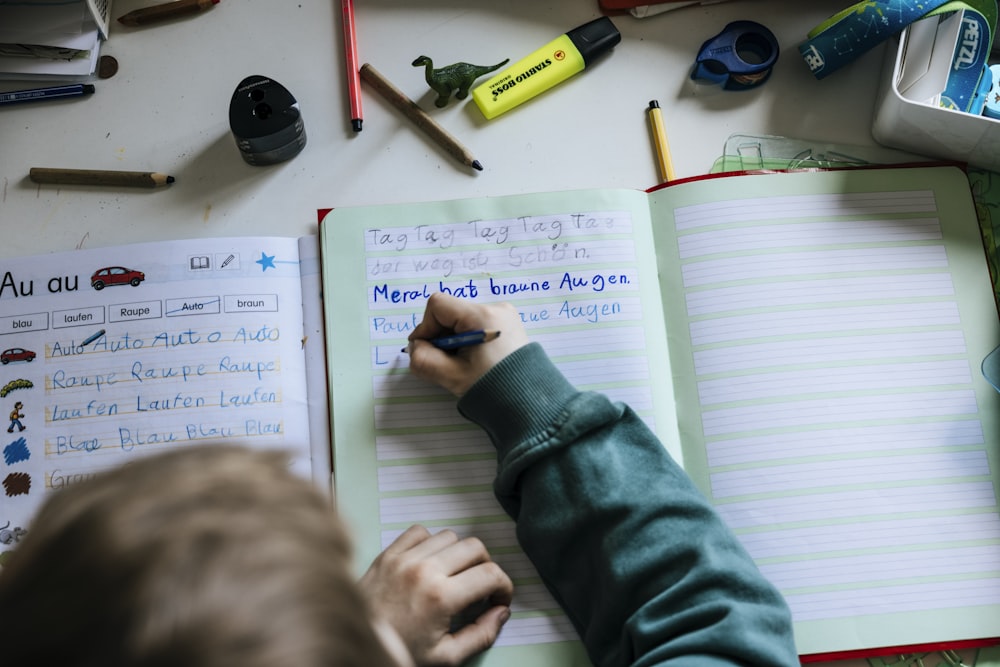 a person writing on a notebook with a pen