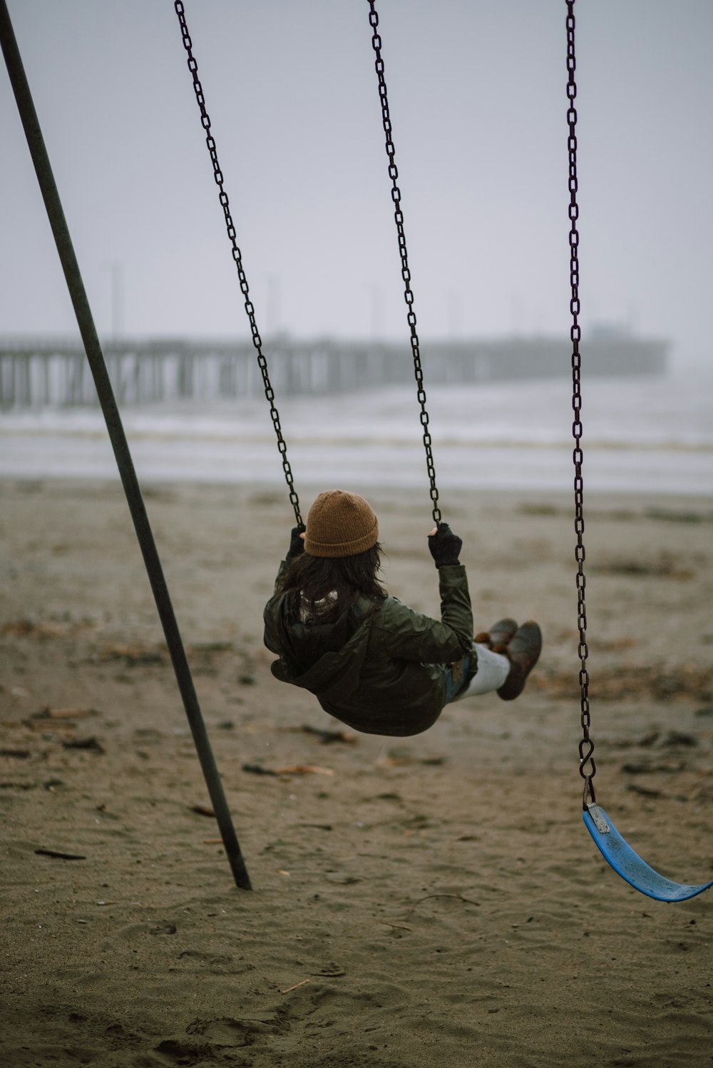 a person swinging on a swing set on a beach
