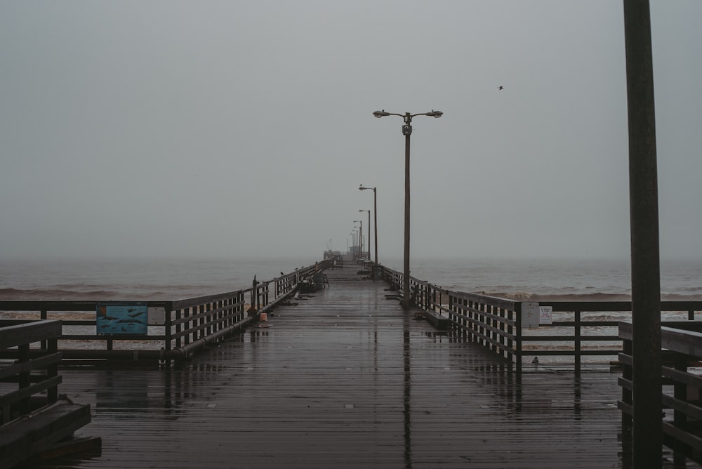 une jetée avec un banc et des lampadaires par temps de brouillard