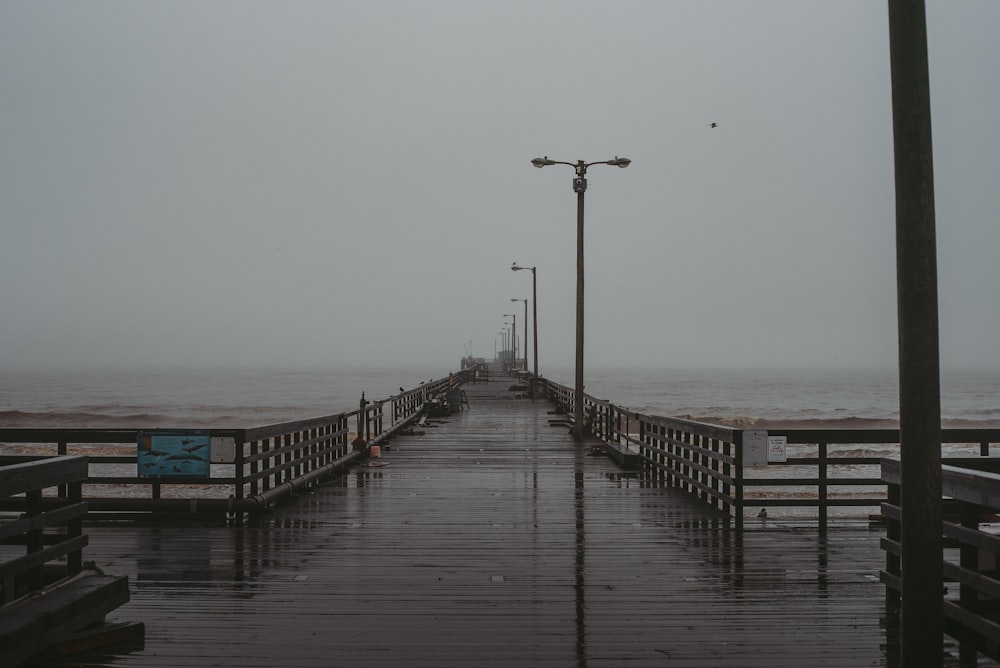 a pier with a bench and street lights on a foggy day