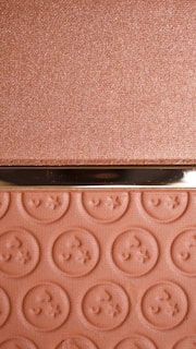 A textured surface with a metallic sheen and a section featuring embossed circular patterns resembling buttons. The upper portion has a shimmery finish, while the lower portion displays repeated embossed designs.