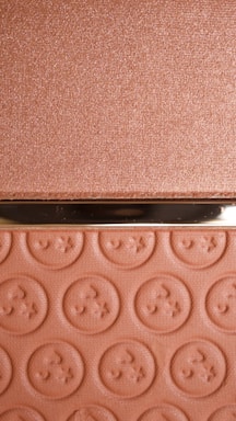 A textured surface with a metallic sheen and a section featuring embossed circular patterns resembling buttons. The upper portion has a shimmery finish, while the lower portion displays repeated embossed designs.