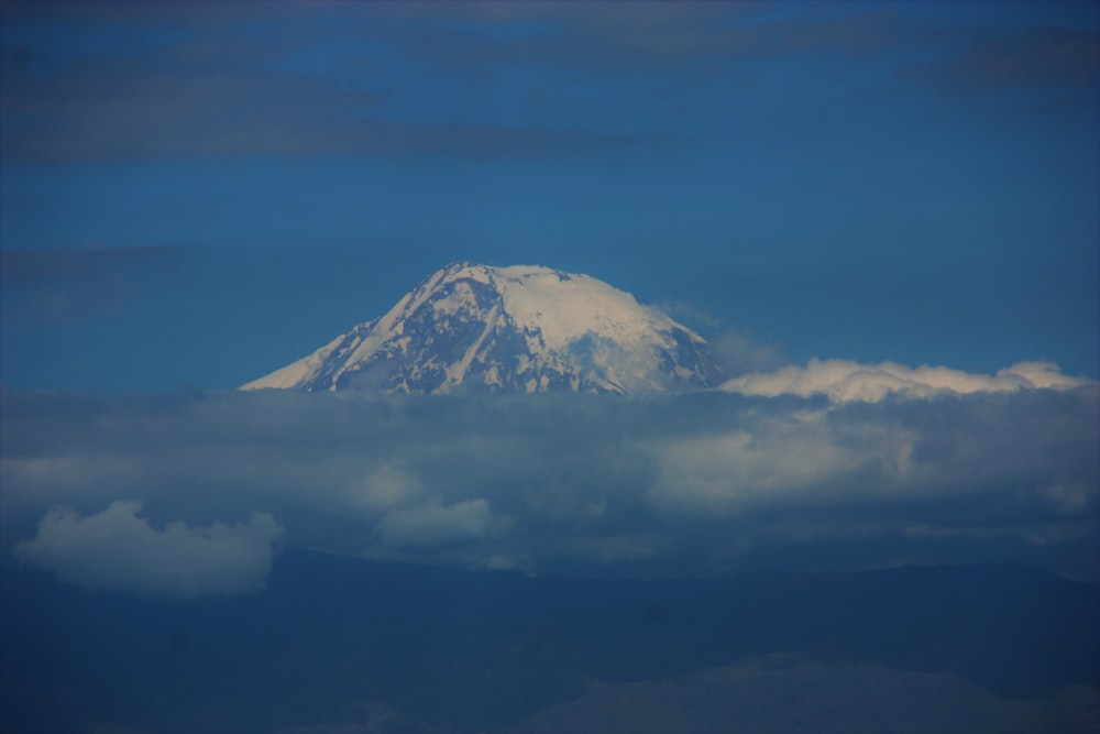 a snow covered mountain in the middle of a blue sky