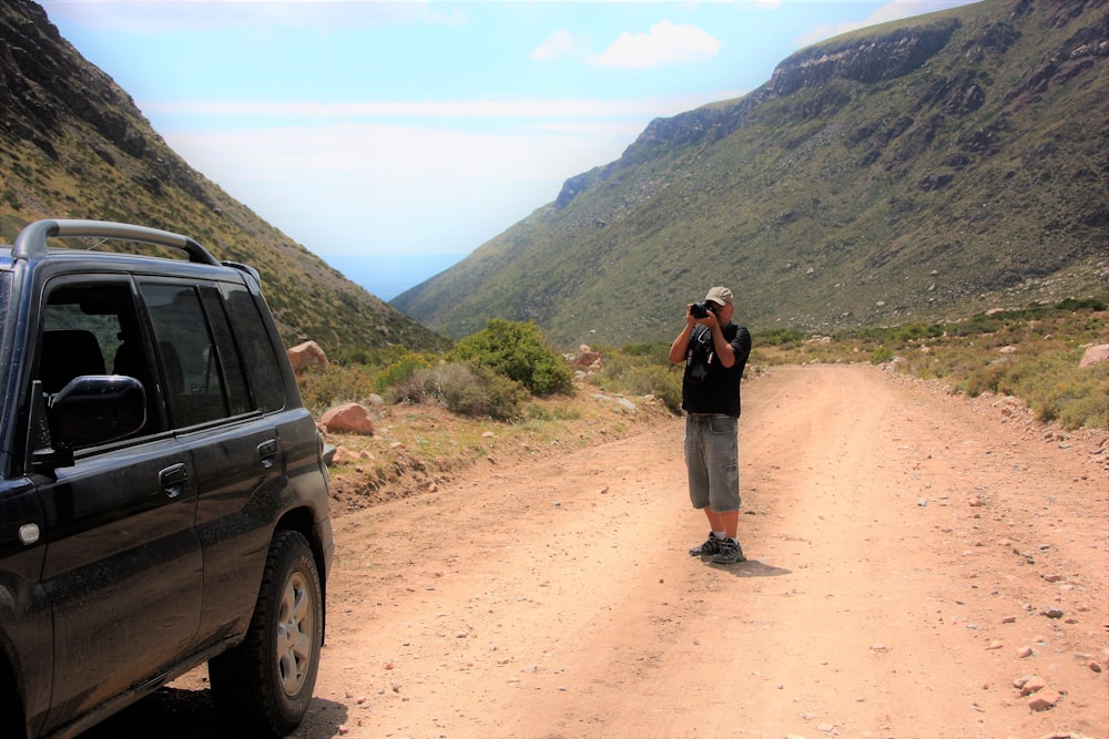 a man standing on a dirt road talking on a cell phone