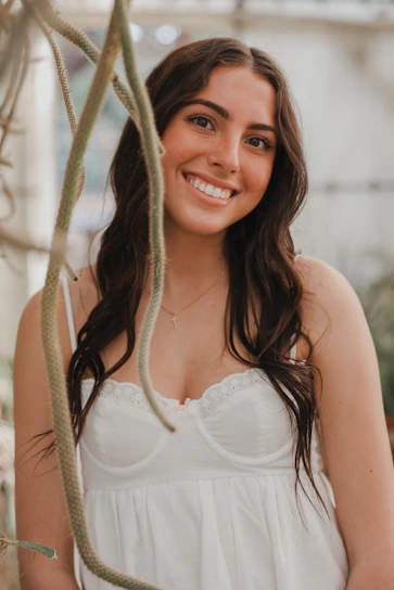 A warm, inviting portrait of a health coach smiling gently in a sunlit room filled with plants.