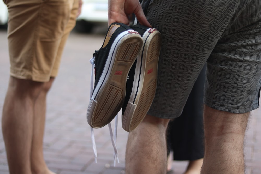 a man holding a pair of shoes while standing next to another man