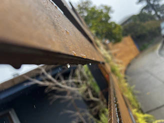 A close-up of a weatherproof fence with water droplets beading on its surface after a rain shower.
