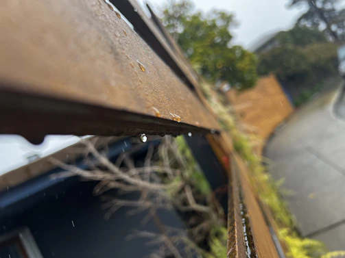 A close-up of a weatherproof fence with water droplets beading on its surface after a rain shower.