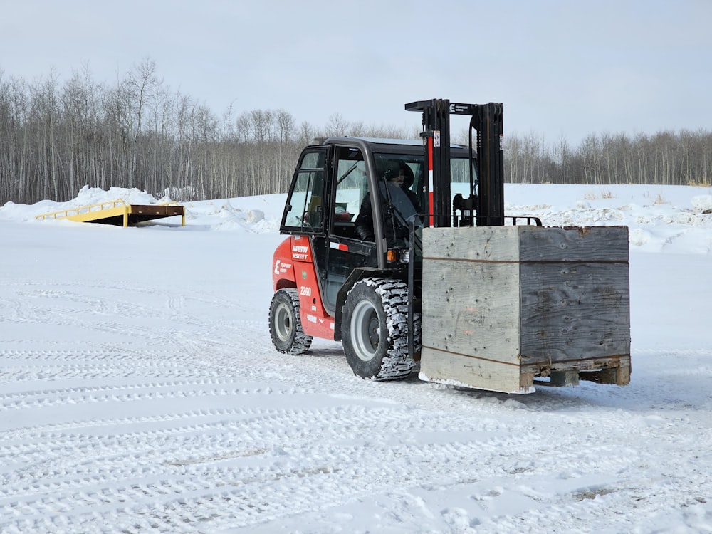 a forklift with a wooden crate on a snowy road