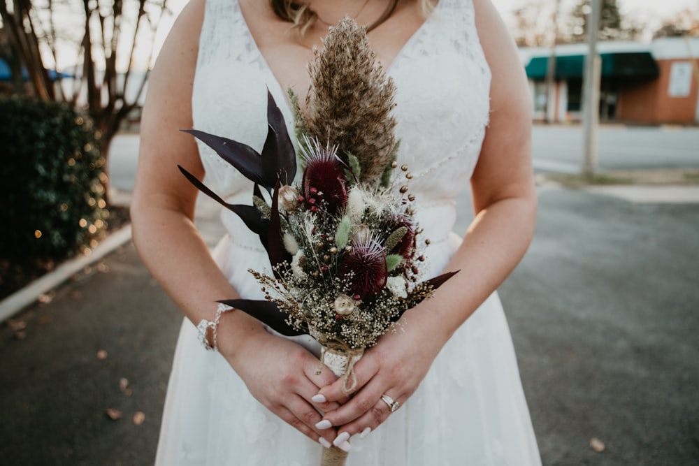 a woman in a white dress holding a bouquet of flowers