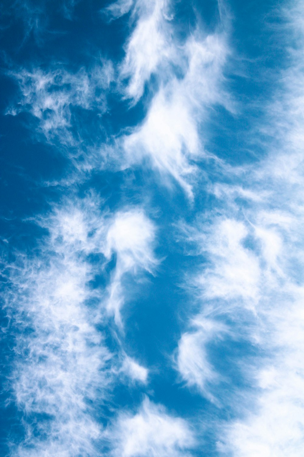 a plane flying through a cloudy blue sky