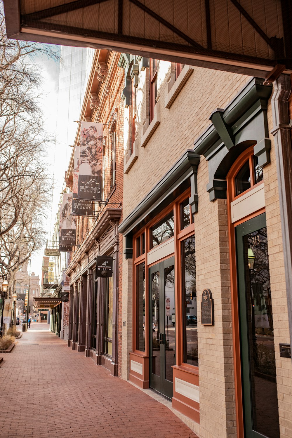 a street with a brick sidewalk and storefronts