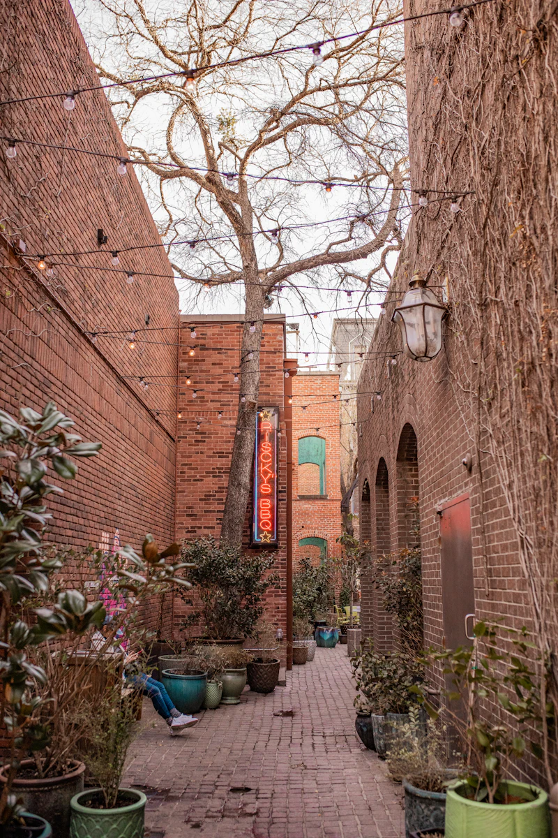 A brick alley with string lights and potted plants in Sundance Square, Fort Worth