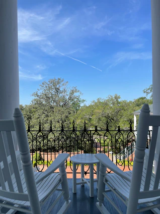 A cozy porch with rocking chairs overlooking a blooming garden at sunset.