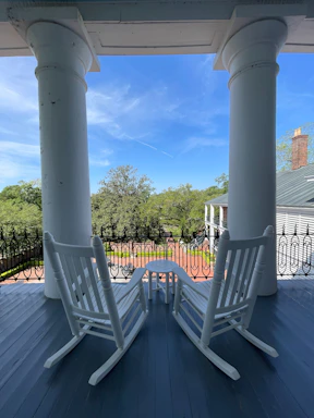 Wide front porch with rocking chairs overlooking a peaceful countryside.