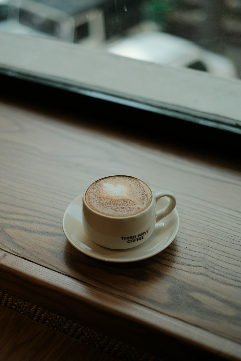 a cappuccino sitting on a saucer on a wooden table