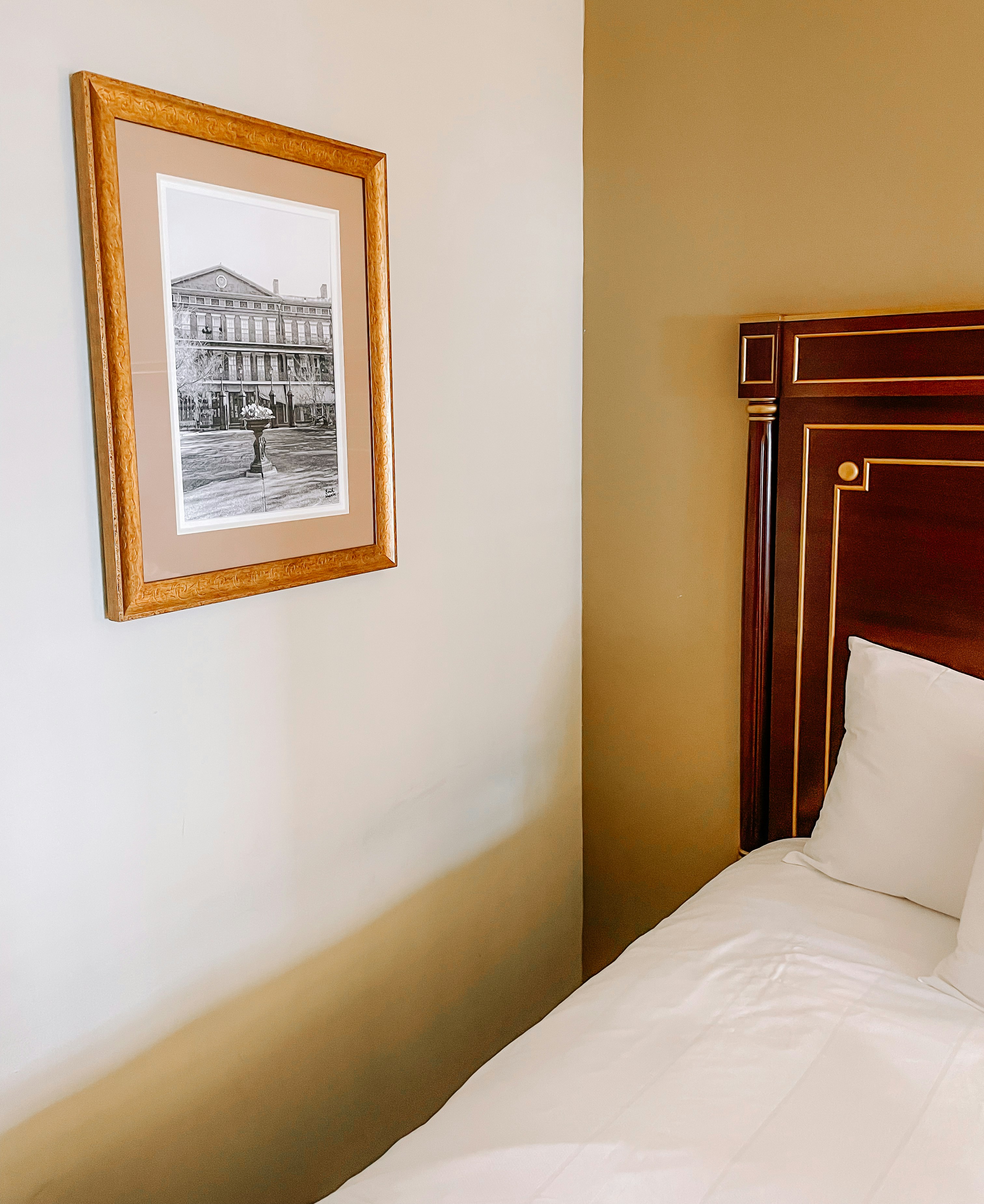 a bed with white sheets and a picture hanging on the wall