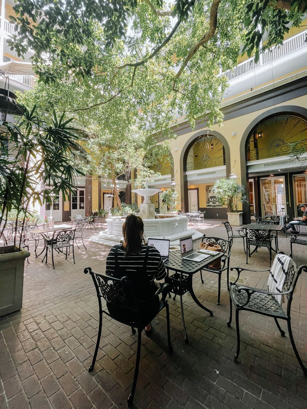 a woman sitting at a table in a courtyard