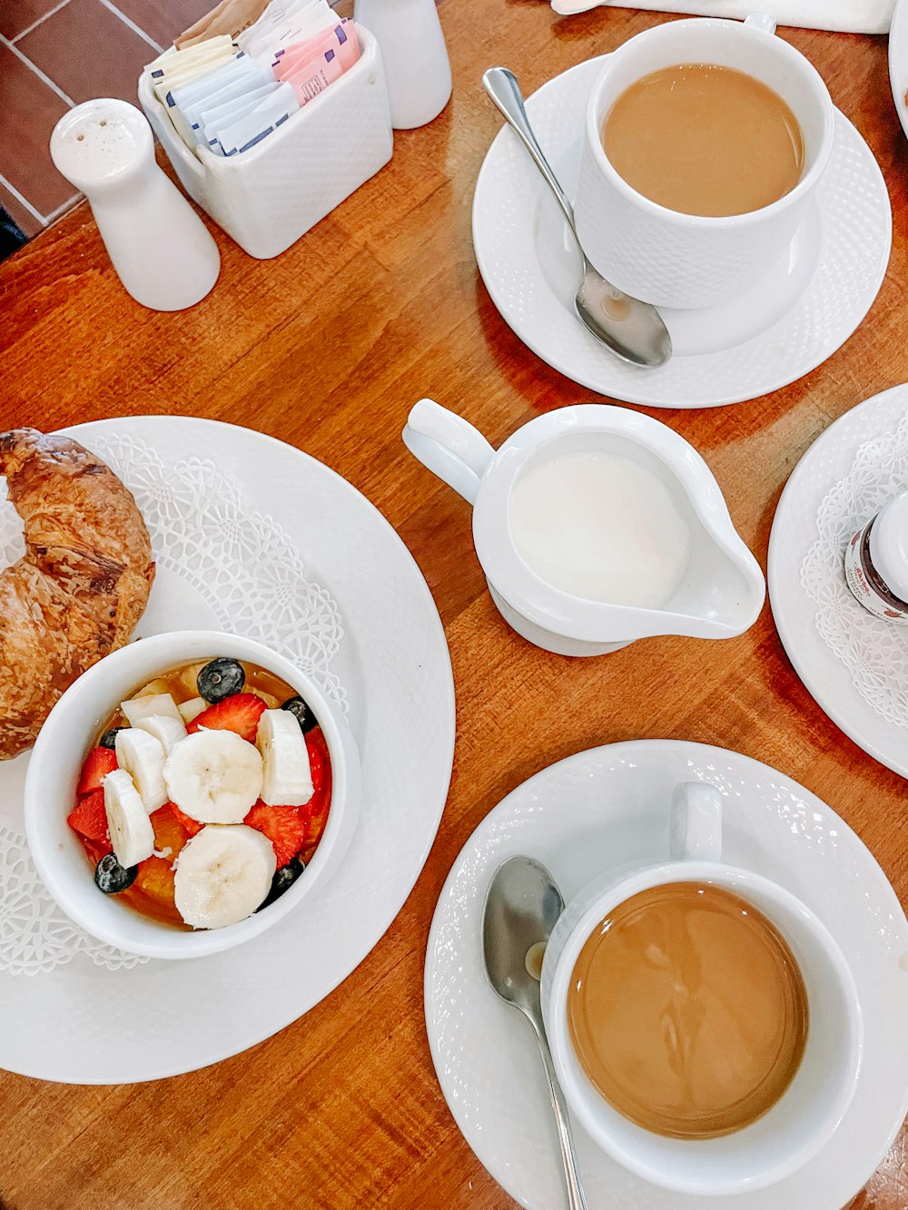 a wooden table topped with plates of food and cups of coffee