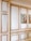 An interior wall featuring elaborate paneling with raised moldings, painted in white and golden hues. Two framed paintings of birdcages and birds are hung side by side on the wall. The style exudes a classic and sophisticated look.