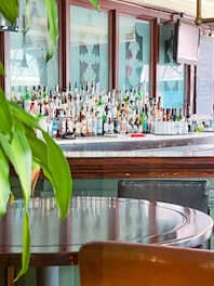 Photo of a cozy bar counter with various drinks and glasses neatly arranged.