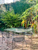 Outdoor granite patio table surrounded by lush greenery under sunlight.