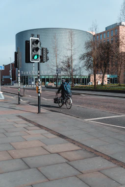 a man riding a bike down a street next to a traffic light