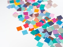 a pile of multicolored confetti sitting on top of a white table