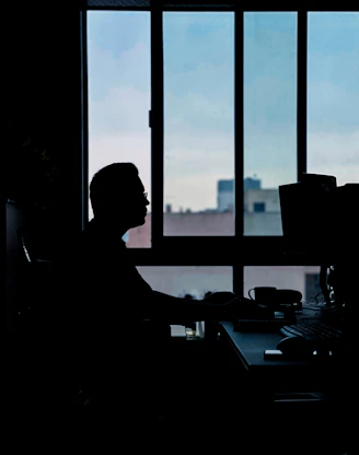 a person sitting at a desk in front of a window