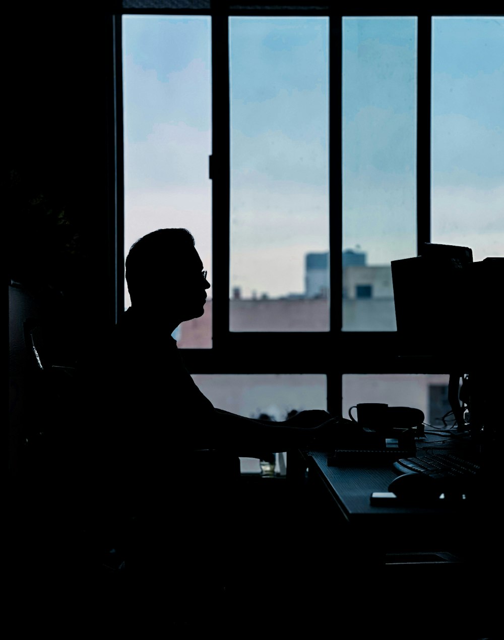 a person sitting at a desk in front of a window