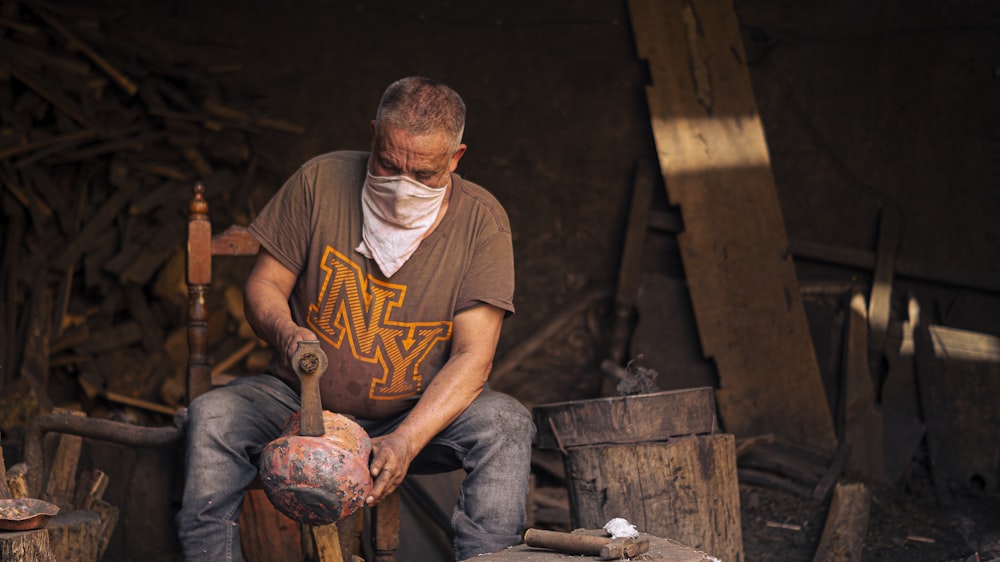 a man sitting in a chair working on a piece of wood
