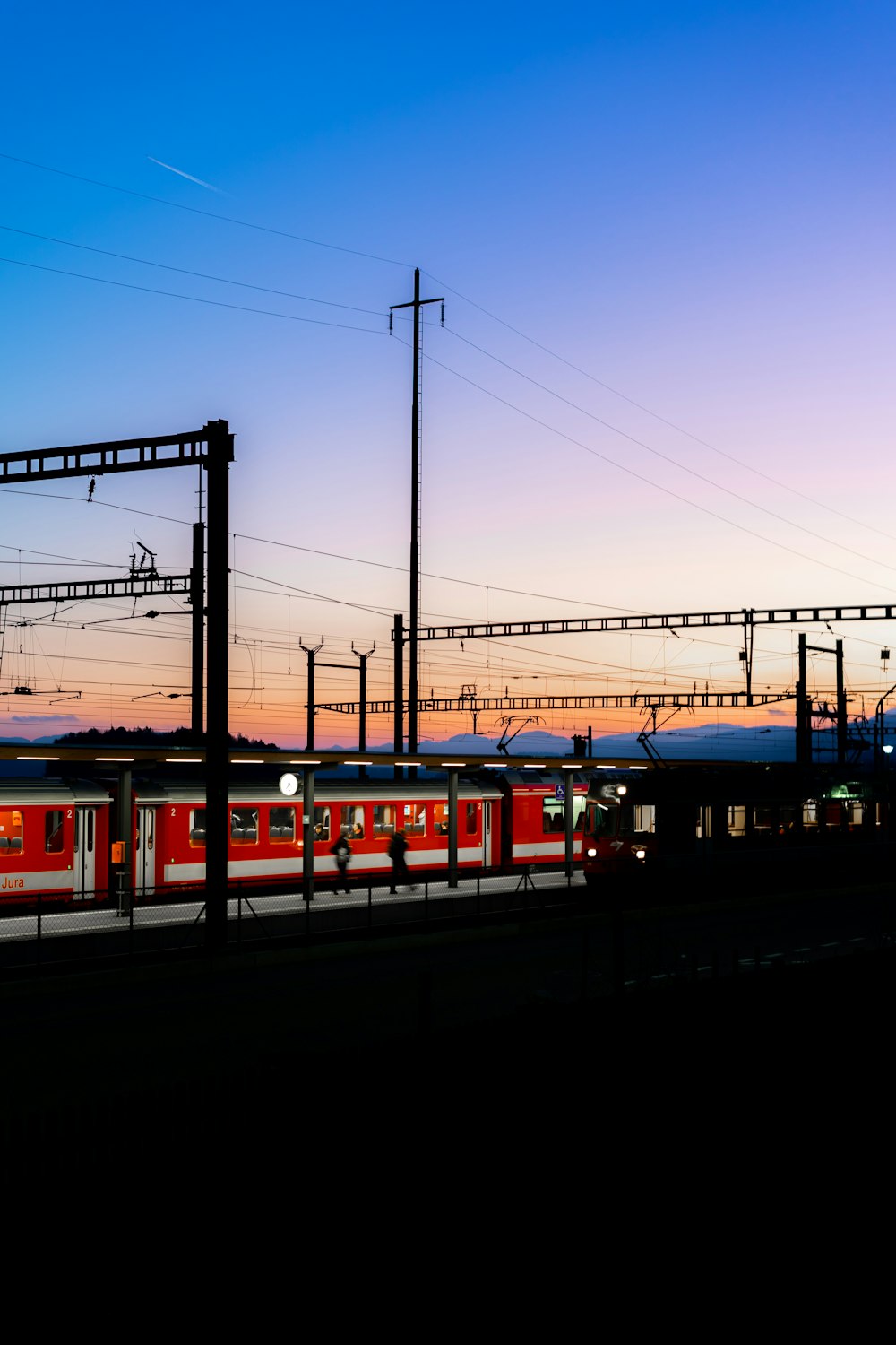a red train traveling down train tracks at dusk