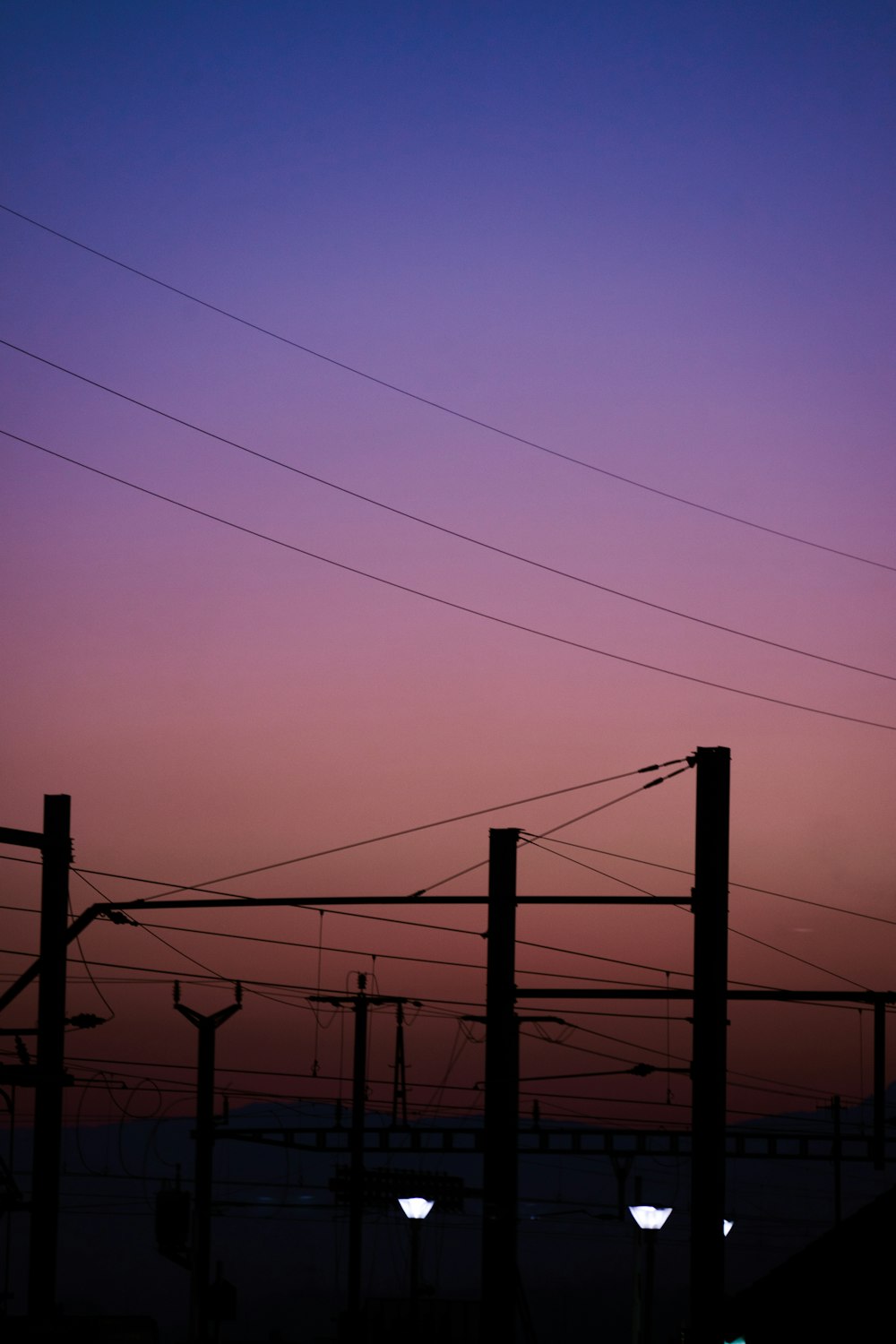 a purple sky with some power lines in the foreground