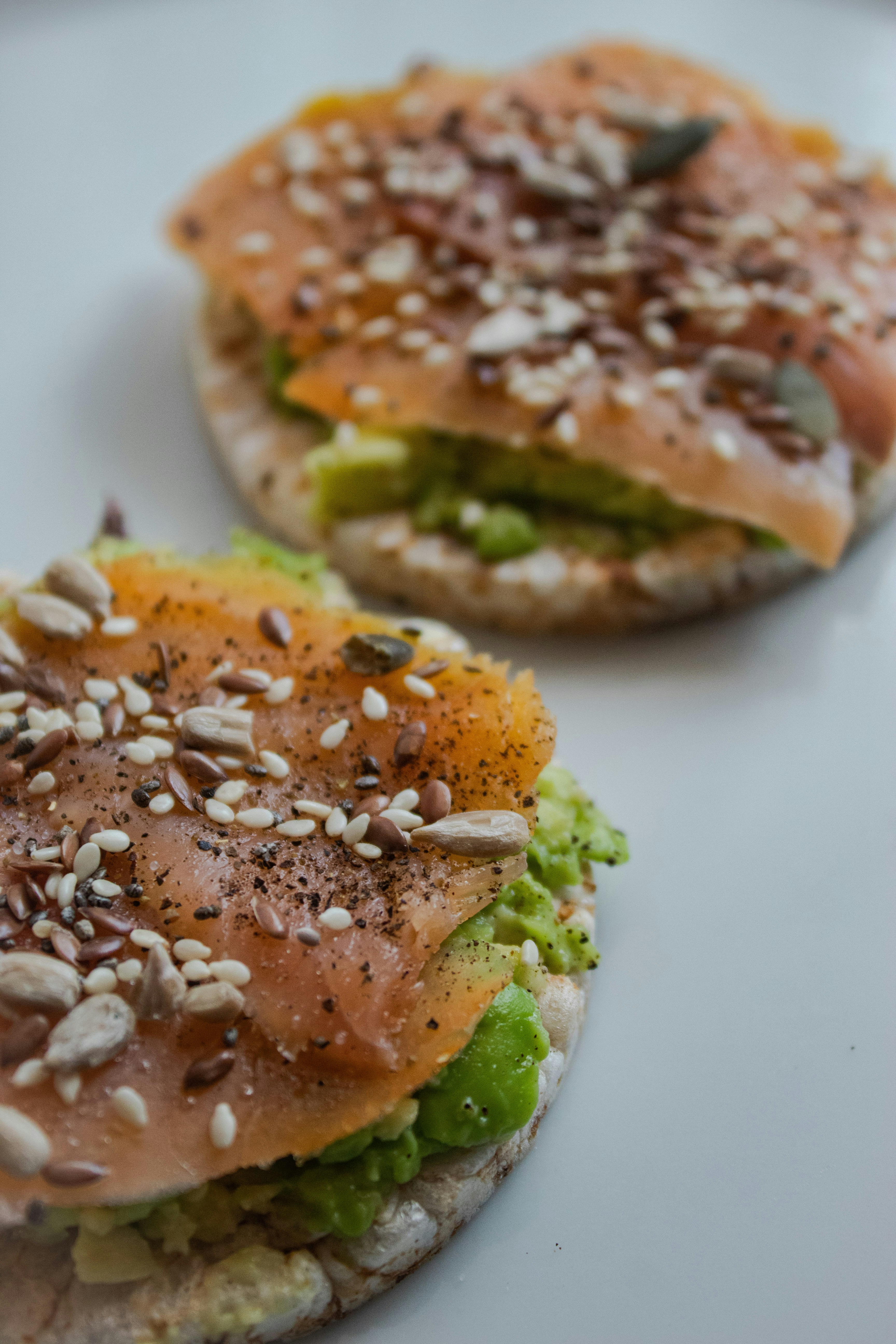 Two crisp brown rice cakes with a light spread of hummus and a sprinkle of paprika