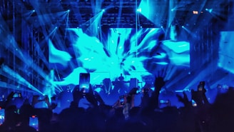 Dynamic shot of a DJ performing live with neon pink and electric blue lighting illuminating the crowd.