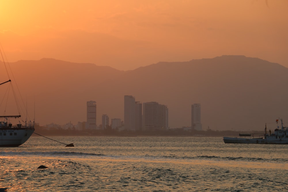 a sailboat in the water with a city in the background